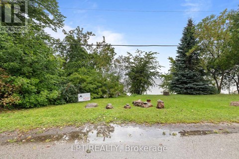 A sign in front of a green area with trees.