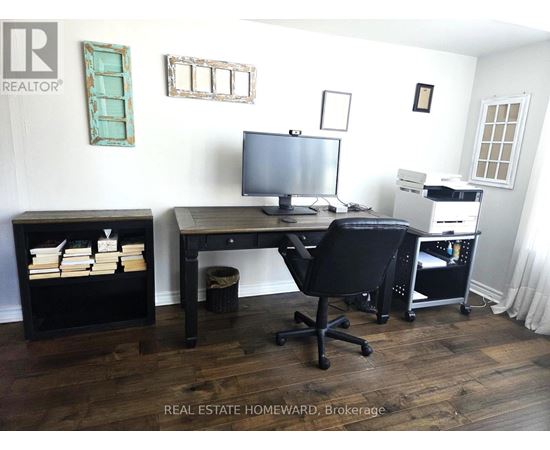 A real estate office with a desk, chair, and computer.