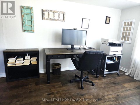 A real estate office with a desk, chair, and computer.