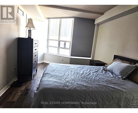 A bedroom with a bed, nightstand, and window.