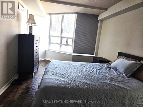 A bedroom with a bed, nightstand, and window.