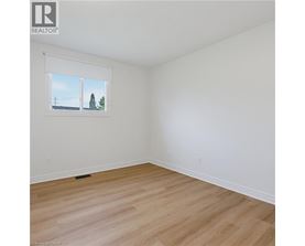 A room with a window showing a view of a house and trees.