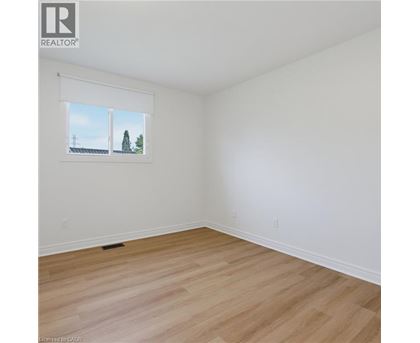 A room with a window showing a view of a house and trees.