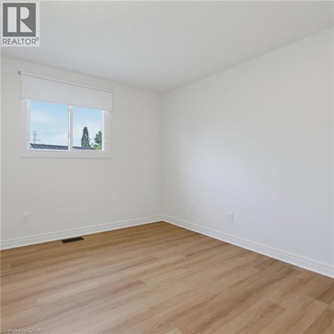 A room with a window showing a view of a house and trees.