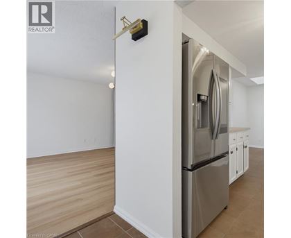 A modern kitchen with a stainless steel refrigerator and wooden flooring.