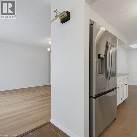 A modern kitchen with a stainless steel refrigerator and wooden flooring.