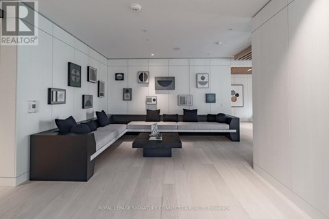 A modern living room with a white wall and a black couch.