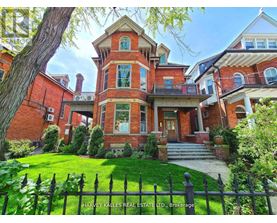 A large red brick house with a black fence in front.