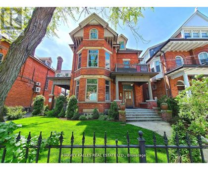 A large red brick house with a black fence in front.
