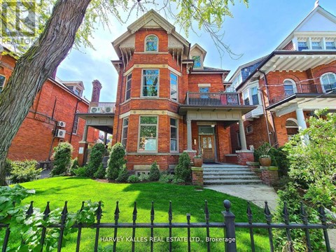 A large red brick house with a black fence in front.