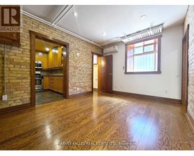 A room with wooden floors and a brick wall with a window.