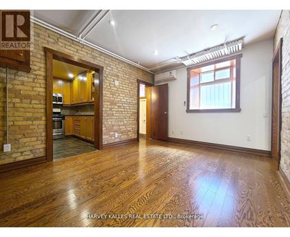 A room with wooden floors and a brick wall with a window.