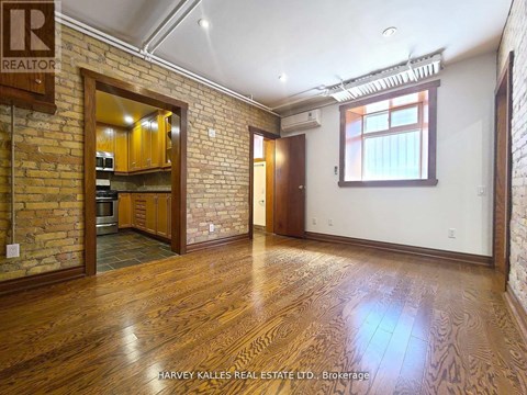 A room with wooden floors and a brick wall with a window.