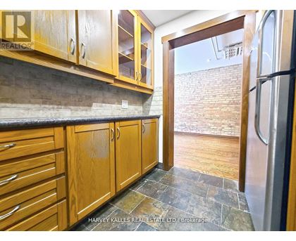 A kitchen with wooden cabinets and a stone floor.