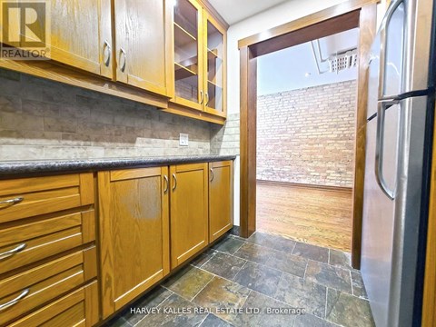 A kitchen with wooden cabinets and a stone floor.