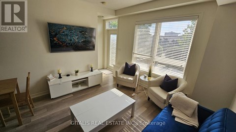 A living room with a blue couch and a painting on the wall.