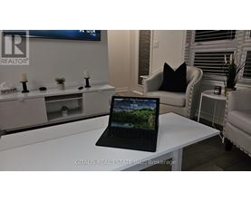 A black laptop is open and displaying a forest scene on a white desk.