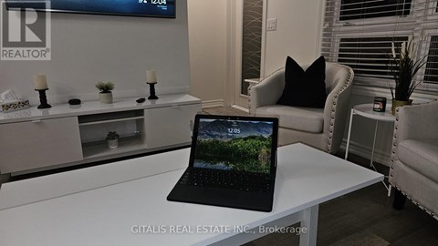 A black laptop is open and displaying a forest scene on a white desk.
