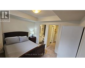 A bedroom with a bed, nightstand, and a doorway leading to another room.