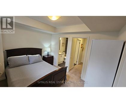 A bedroom with a bed, nightstand, and a doorway leading to another room.