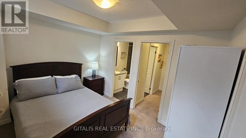 A bedroom with a bed, nightstand, and a doorway leading to another room.