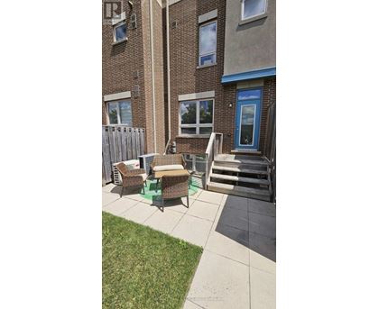 A patio with a table and chairs is in front of a brick building.