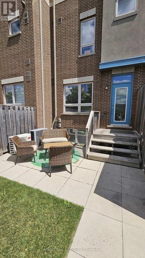 A patio with a table and chairs is in front of a brick building.