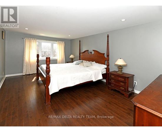 A bedroom with a large bed and wooden floors.
