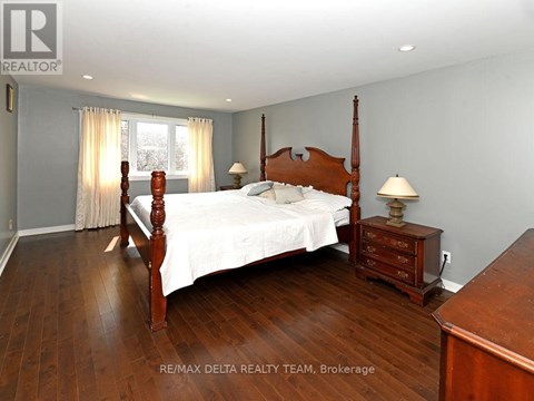 A bedroom with a large bed and wooden floors.