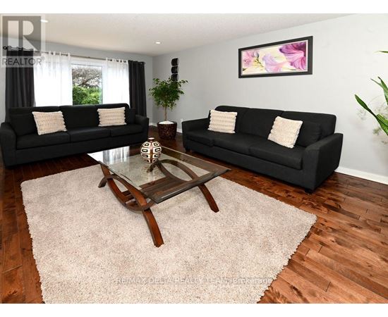 A living room with black couches and a glass coffee table.