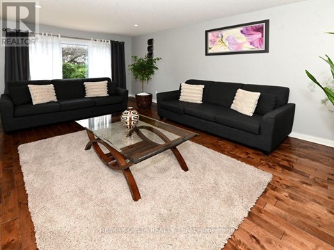 A living room with black couches and a glass coffee table.