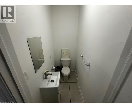 A bathroom with a toilet, sink, and mirror.
