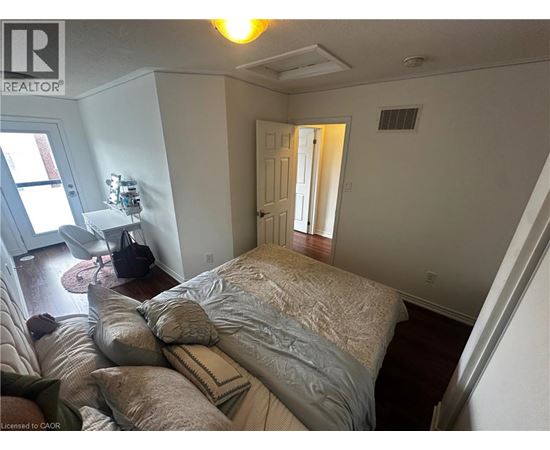 A bedroom with a bed, pillows, and a chair.