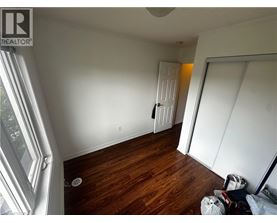 A room with wooden floors and white walls, with a door in the background.