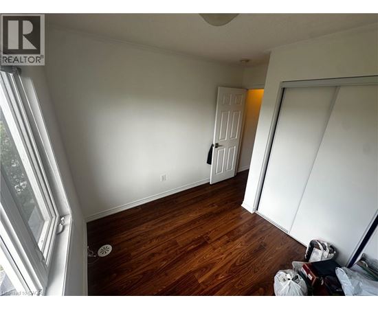A room with wooden floors and white walls, with a door in the background.