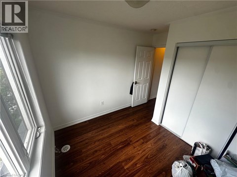 A room with wooden floors and white walls, with a door in the background.