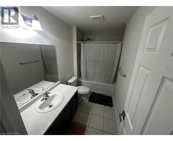 A bathroom with a white sink, toilet, and shower curtain.