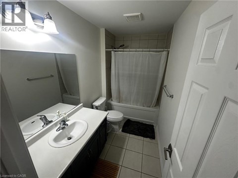 A bathroom with a white sink, toilet, and shower curtain.