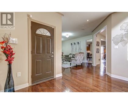 A living room with a brown door and a vase of red flowers on a table.