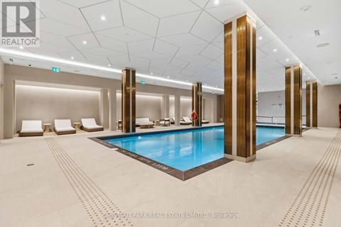 A large indoor swimming pool with a tiled floor and a tiled wall.