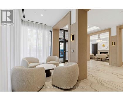 A living room with a white sofa and a white chair with a brown cushion.