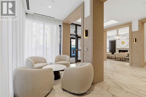 A living room with a white sofa and a white chair with a brown cushion.