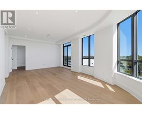 A spacious room with wooden flooring and large windows.