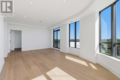 A spacious room with wooden flooring and large windows.