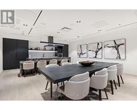A dining room with a black table and white chairs.