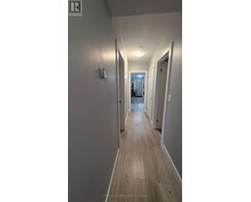 A long hallway with wood floors and white walls.