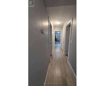 A long hallway with wood floors and white walls.