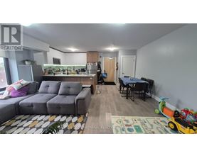 A living room with a grey sofa, a dining table with chairs, and a play area with toys.
