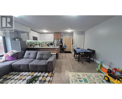 A living room with a grey sofa, a dining table with chairs, and a play area with toys.