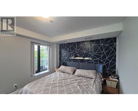 A bedroom with a bed, nightstand, and window.